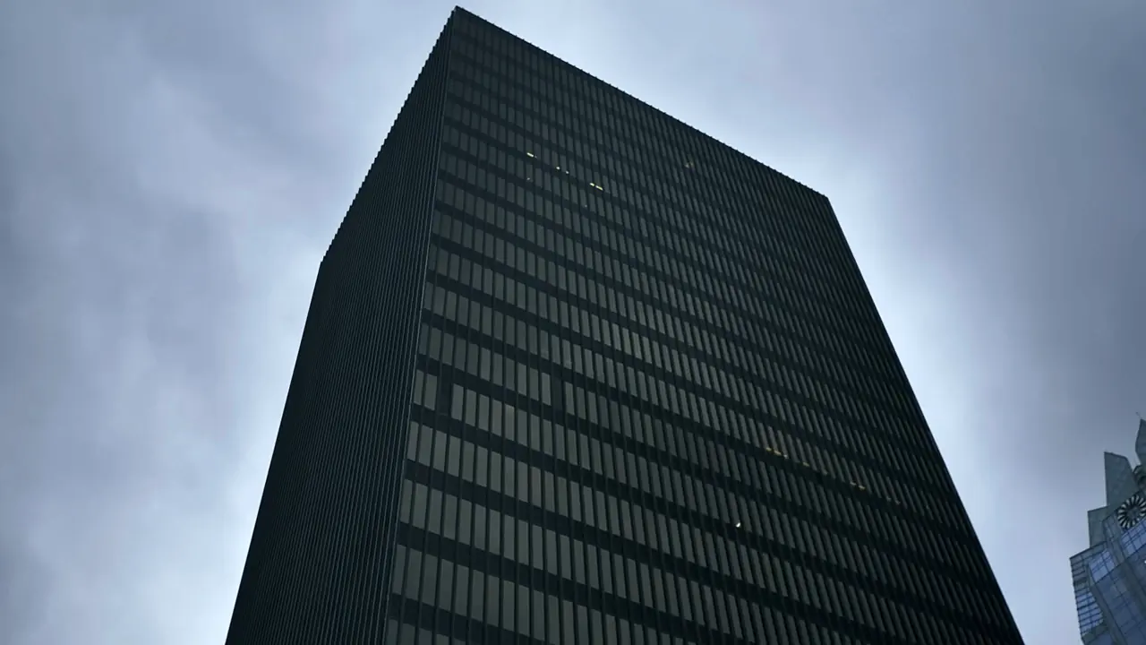 A tall office tower against an overcast sky, seen from street level