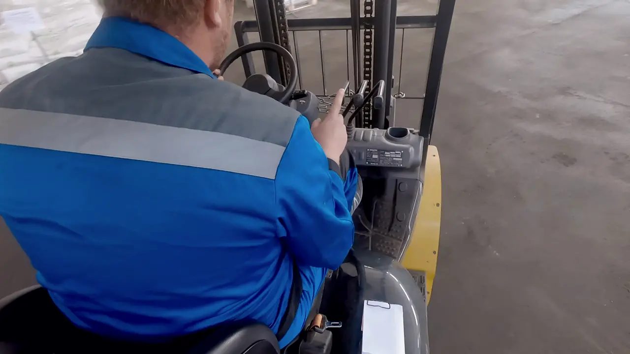 A forklift operator driving across a warehouse floor